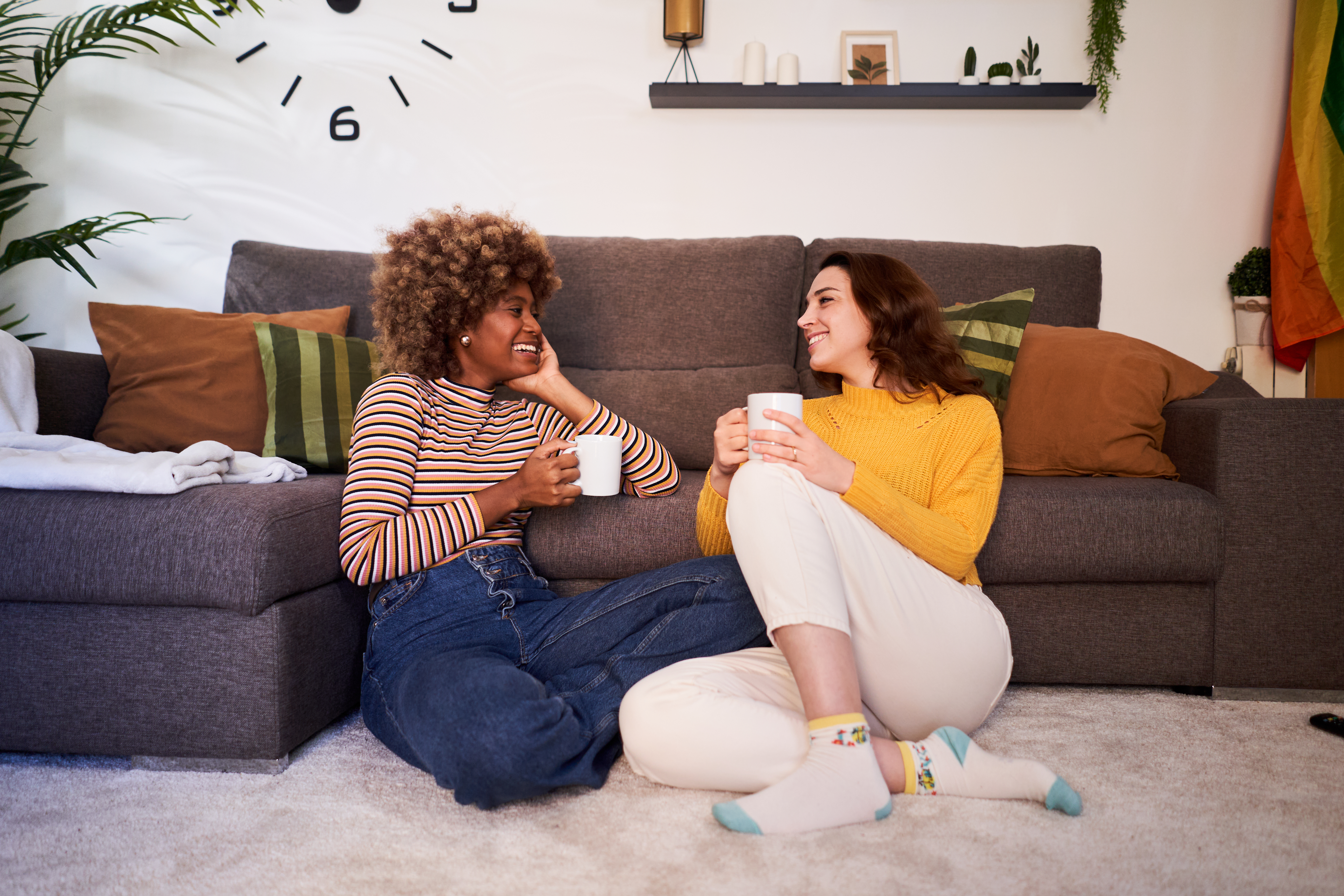 Happy young lesbian couple relaxing together in their living room at home.